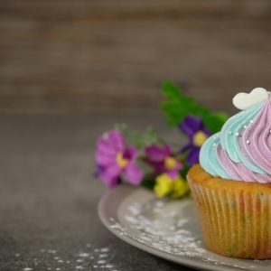 A pastel frosted cupcake with flowers on a plate, perfect for desserts and celebrations.