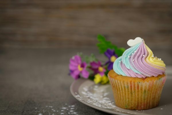 A pastel frosted cupcake with flowers on a plate, perfect for desserts and celebrations.